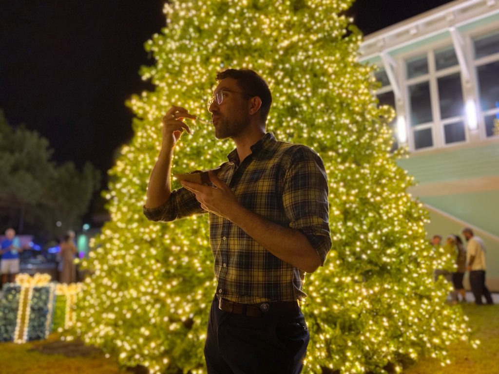 man enjoying a food in front of christmas tree