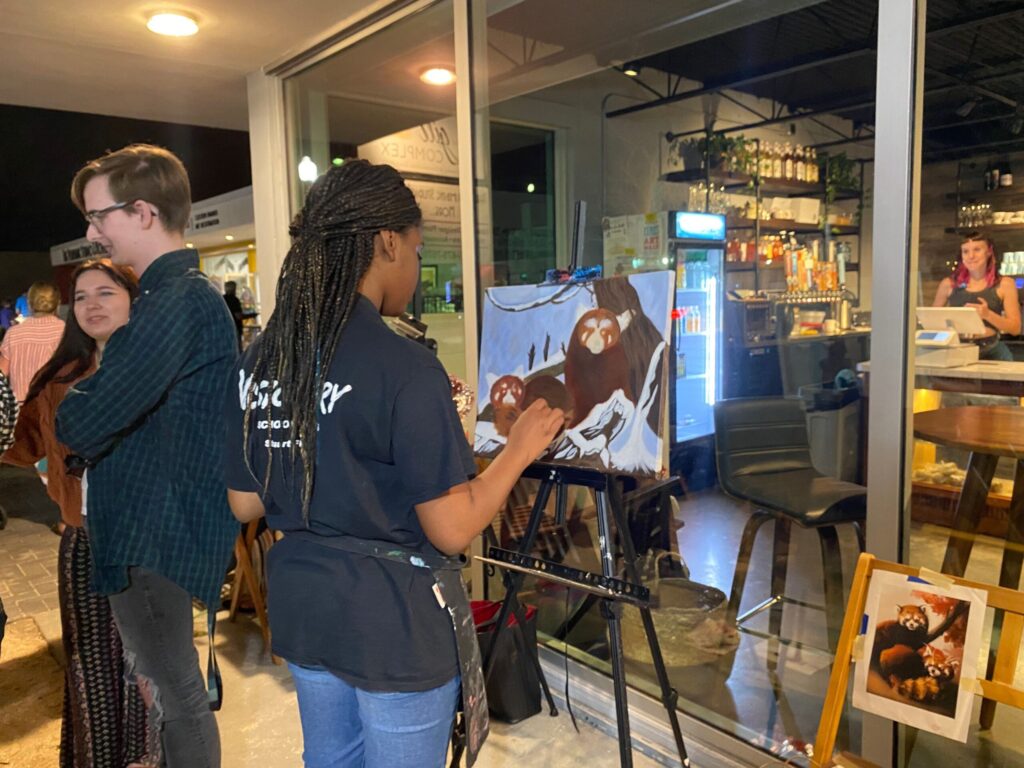 woman midway through painting red pandas